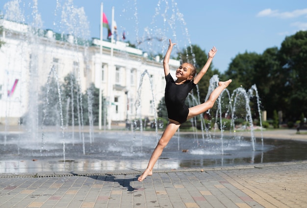 Бесплатное фото Маленькая девочка с удовольствием у фонтана