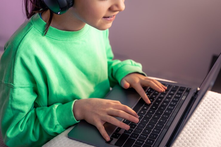 Free Photo little girl in headphones plays a game on the computer in the room
