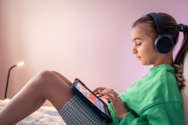 Free photo little girl in headphones with a tablet in her room