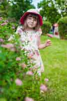 Foto gratuita la bambina dietro una siepe di fiori in una mano