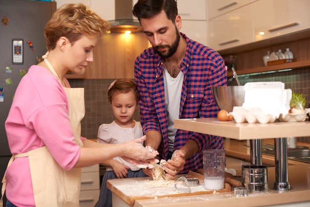 Little girl helping parents at the kitchen