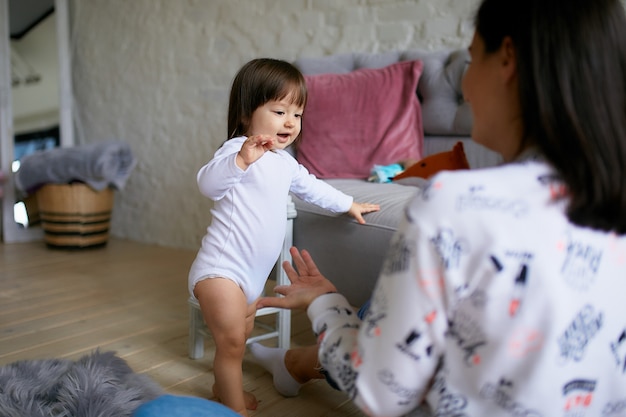 캐주얼 스타일을 입은 어린 소녀와 그녀의 엄마는 바닥에서 놀고 재미있다.