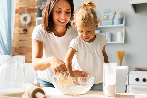 Little girl and her mother preparing dough