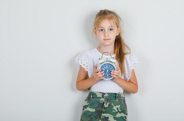 Free photo little girl holding alarm clock in white t-shirt