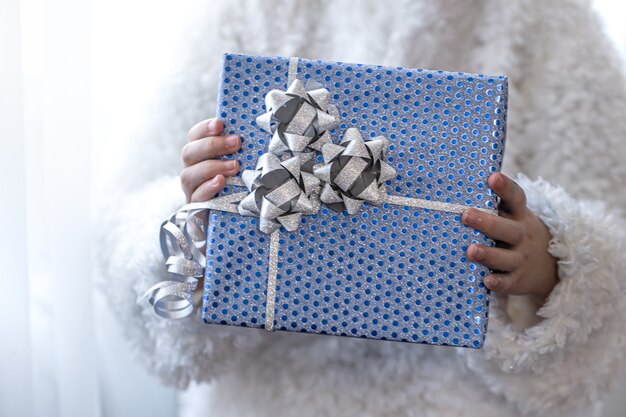 A little girl holding a blue holiday gift.