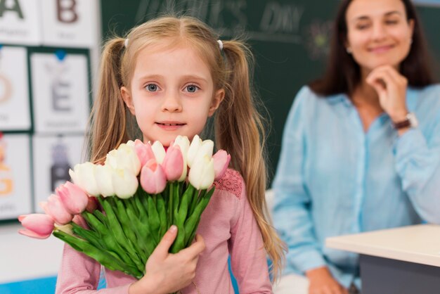 彼女の先生のための花の花束を保持している小さな女の子