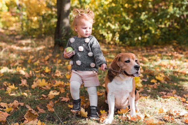Маленькая девочка держит собачий поводок в парке