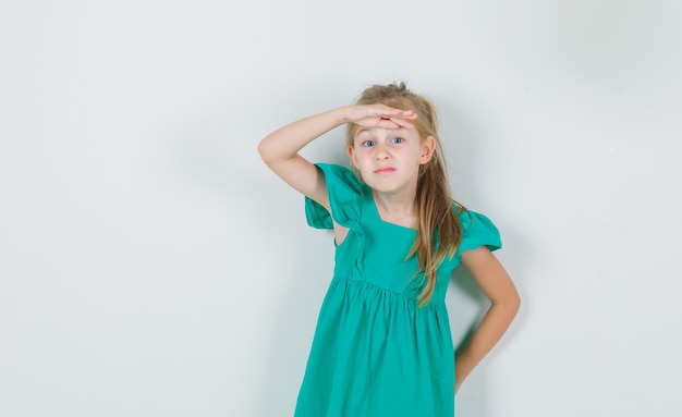 Free photo little girl holding hand over eyes in green dress