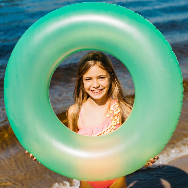 Маленькая девочка держит надувное плавательное кольцо