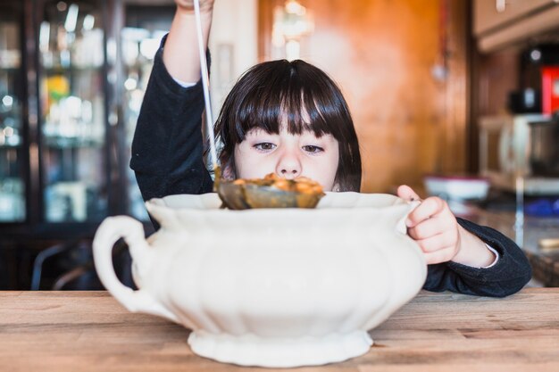 Little girl holding scoop with soup in hand