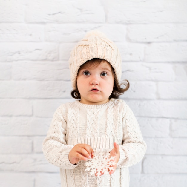 Little girl holding a snowflake and looking at photographer