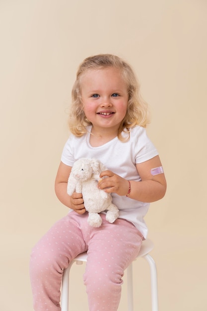 Free photo little girl holding toy after getting a vaccine