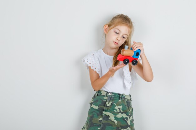 白いtシャツでおもちゃの列車を保持している小さな女の子