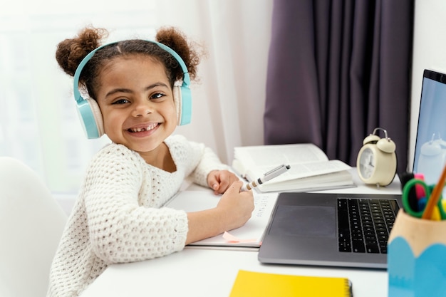 Free photo little girl at home during online school with laptop and headphones