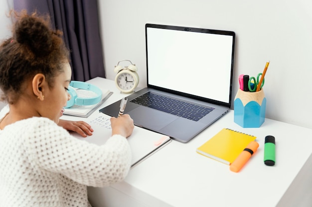 Маленькая девочка дома во время онлайн-школы, используя ноутбук
