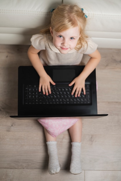 Little girl at home playing on laptop