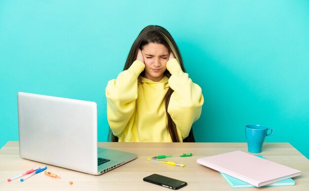 좌절과 귀를 덮고 고립 된 파란색 배경 위에 노트북 테이블에 어린 소녀