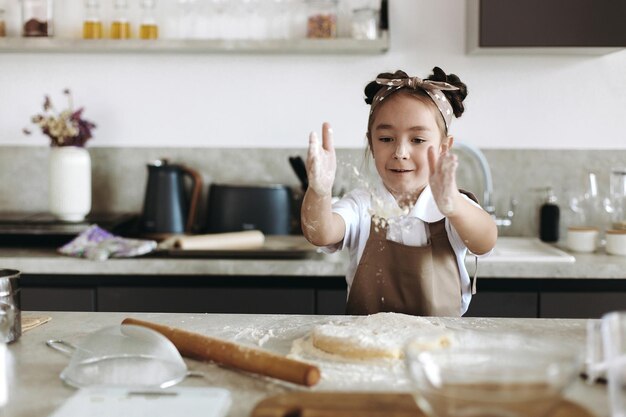 어린 소녀가 부엌에서 쿠키를 요리하고 있다