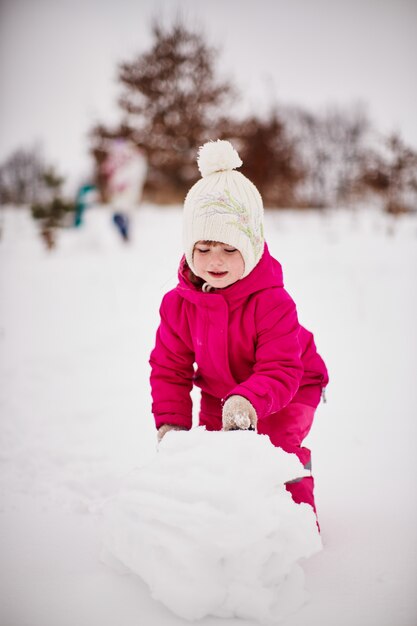 小さな女の子は雪で遊んで喜ぶ