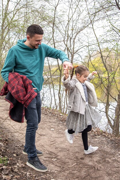 A little girl is a whirl, holding her dad's hand for a walk in the woods.