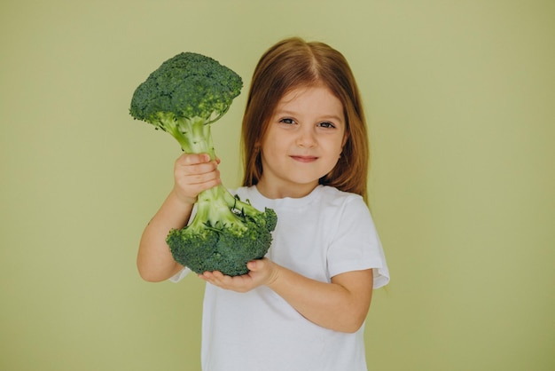 Little girl isolated holding green raw broccoli