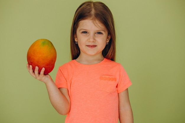 Бесплатное фото Маленькая девочка изолирована, держа манго