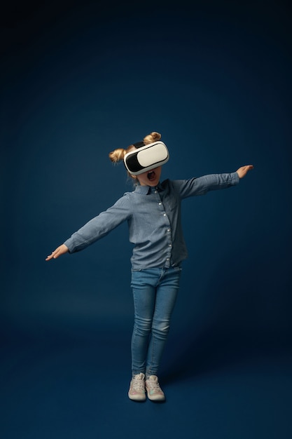 Free photo little girl in jeans and shirt with virtual reality headset glasses isolated