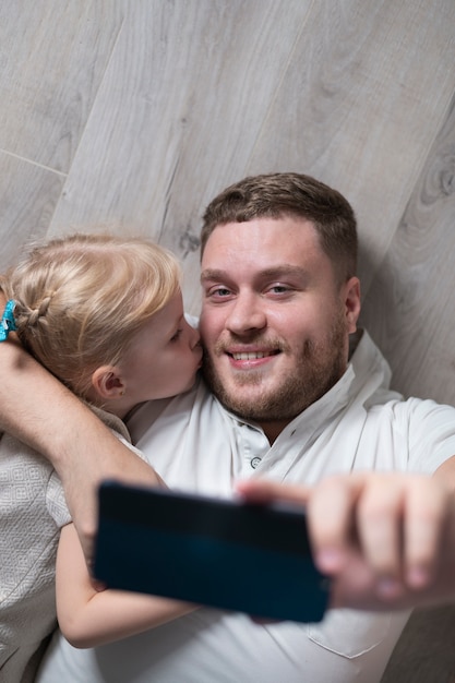 Little girl kissing father while taking selfie 