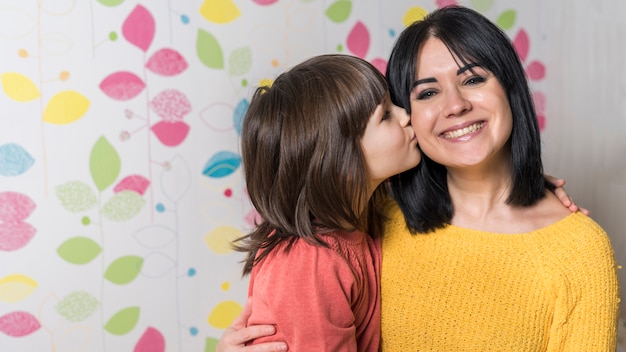 Little girl kissing mother on cheek