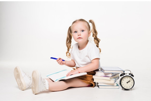 Little girl laying on the floor and drawing pictures in a notebook isolated