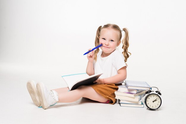 Little girl laying on the floor and drawing pictures in a notebook isolated