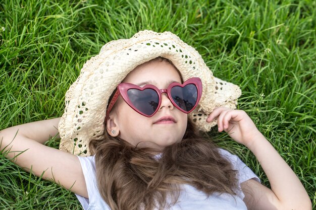 маленькая девочка лежит в траве летнее время и солнечный день