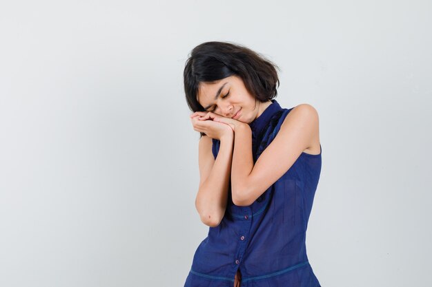 Little girl leaning on hands as pillow in blue blouse and looking cute.