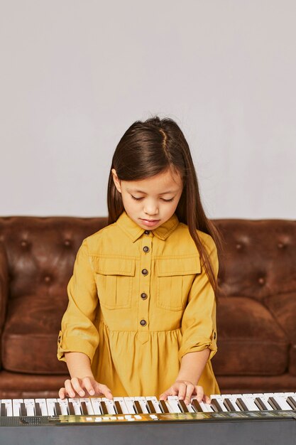 Little girl learning how to play electronic keyboard at home