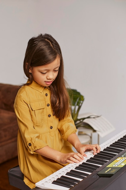 전자 키보드를 연주하는 방법을 배우는 어린 소녀