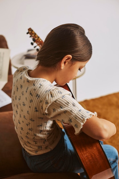 Little girl learning how to play guitar at home