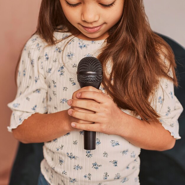 Little girl learning how to sing at home with microphone