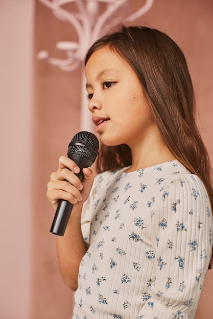 Bambina che impara a cantare a casa con il microfono