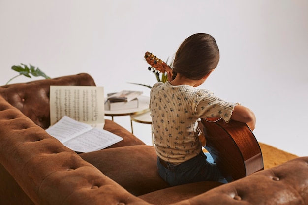 Маленькая девочка учится играть на гитаре дома