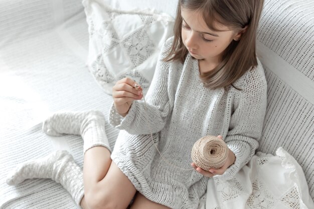 Little girl learning to knit, home leisure and needlework concept.