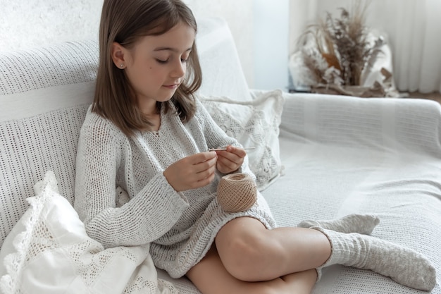뜨개질, 가정 여가 및 바느질 개념을 배우는 어린 소녀.