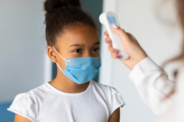 Free photo little girl letting someone to take her temperature