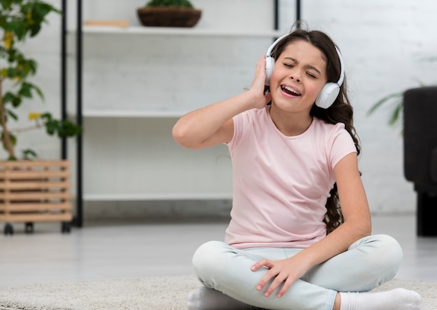 Маленькая девочка слушает музыку через наушники в помещении
