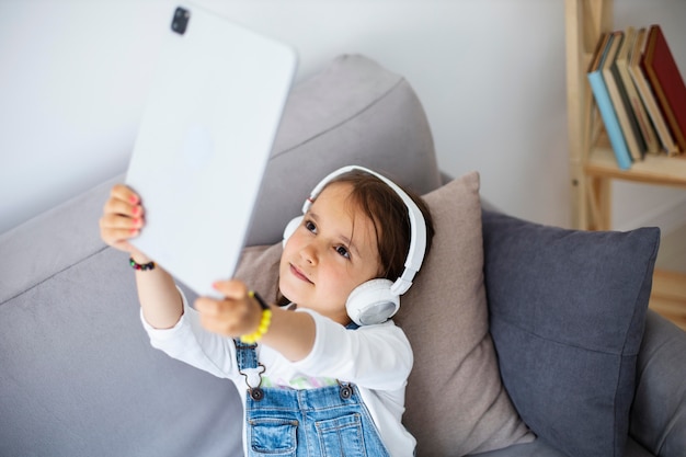 Free photo little girl listening to music through headphones