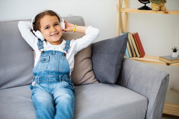 Free photo little girl listening to music through headphones