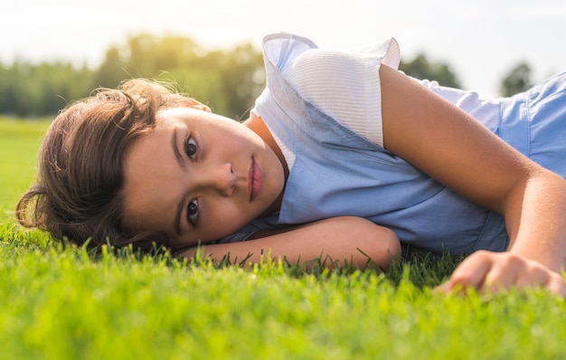 Маленькая девочка смотрит в камеру, оставаясь на траве