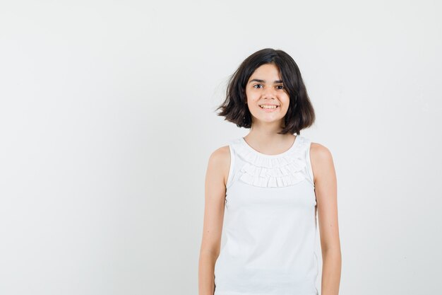 Little girl looking at front in white blouse and looking glad. front view.