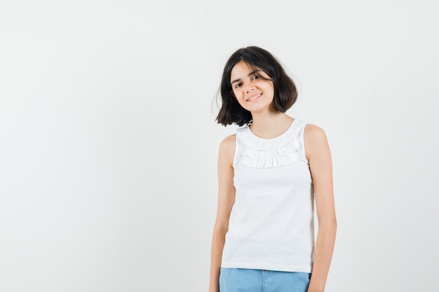 Little girl looking at front in white blouse, shorts and looking beautiful. front view.