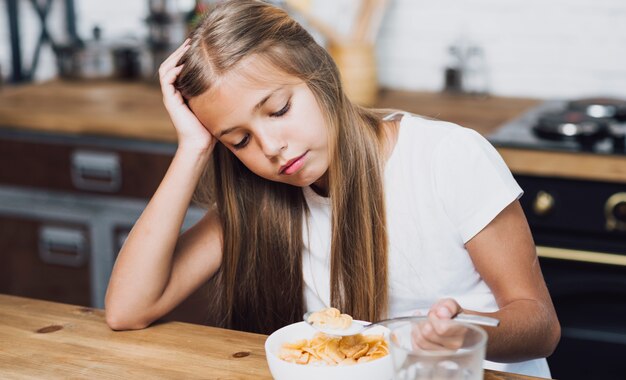 Bambina che esamina la sua ciotola con cereale