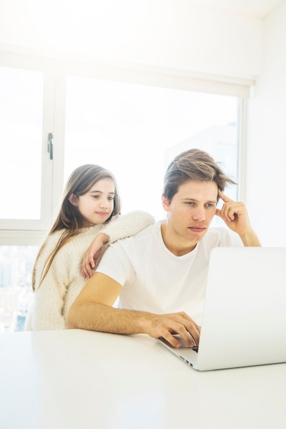 Little girl looking at laptop screen with his father